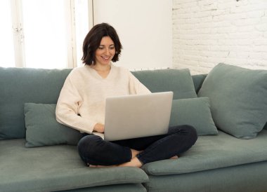 Genç çekici portresi yaşam tarzı ve çalışma veya evde eğitim bilgisayar, zevk online film seyrederken, kullanan rahat kadın kanepede mutlu gülümseyerek. İnternet ve sosyal ağ kavramı.