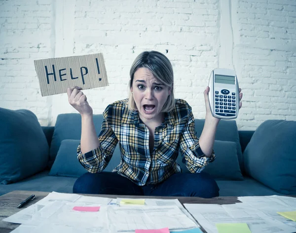 Worried young woman feeling stressed while accounting business and home finances. Desperate showing Help sign and calculator. In bad economic situation, paying debts, bills and financial problems.