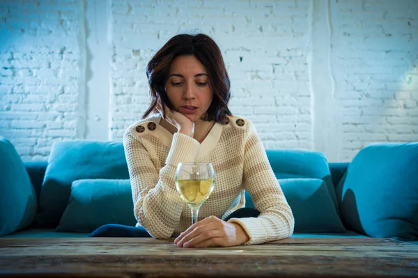 Portrait of depressed woman drinking glass of wine alone at home. Feeling distress, hopeless and frustrated, trying to feel better drinking. Unhealthy behavior, depression and alcohol concept.
