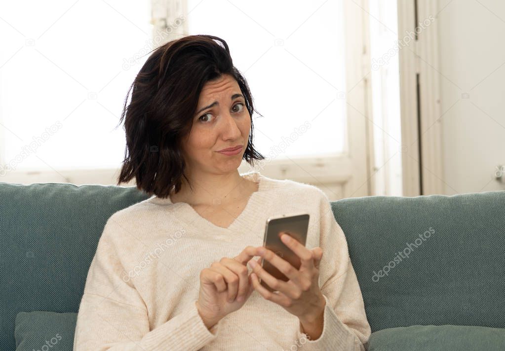 Lifestyle portrait of attractive woman on smart mobile phone Sending messages, chatting or in social media smiling happy on the couch at home. In leisure internet and social network addiction.