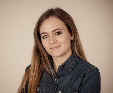 Küçük güzel genç kadının stüdyo portresi, sarı saçlı, kendine güvenen, rahat poz veren ve modelleme yapan Jean shirt giyiyor. Nötr arka planda izole. Yaşam tarzı ve güzellik konsepti.