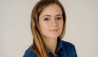Küçük güzel genç kadının stüdyo portresi, sarı saçlı, kendine güvenen, rahat poz veren ve modelleme yapan Jean shirt giyiyor. Nötr arka planda izole. Yaşam tarzı ve güzellik konsepti.