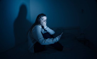 Online BULLING ve taciz yalnız ve umutsuz gece yatakta oturan felling acı akıllı telefonda üzücü umutsuz genç ergen kadın kız. Siber zorbalık ve internet kavramının tehlikeleri.