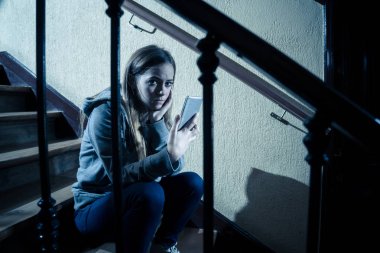 Siber zorbalık istismarı muzdarip online Stalker genç kız kurbanı yalnız ve umutsuz koyu ışık merdivenlerde oturan duygu. İnternet tehlikeleri, çevrimiçi bakım ve taciz konsepti.