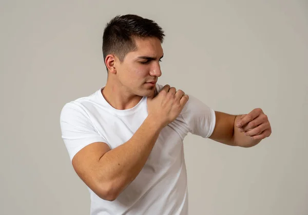 年轻的肌肉健身男子触摸和抓住他的肩膀遭受强烈的疼痛 在中性背景上隔离 在运动损伤不正确的姿势问题和身体保健 — 图库照片