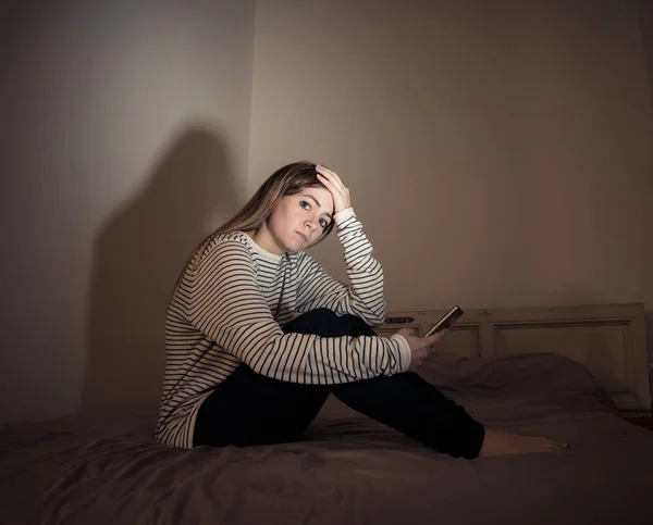 スマートフォン上の悲しい絶望的な若い十代の女の子は オンラインのいじめとハラスメントに苦しむ夜にベッドの上で座って孤独と絶望を伐採 ネットいじめとインターネット概念の危険性 — ストック写真