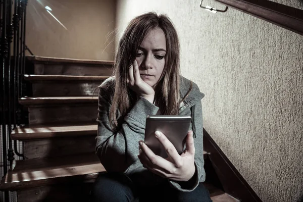 十代の女の子がネットいじめに苦しむオンラインストーカーの被害者暗い光と階段に座って孤独と絶望的な感じ インターネットの危険性 オンライングルーミングとハラスメントの概念 — ストック写真