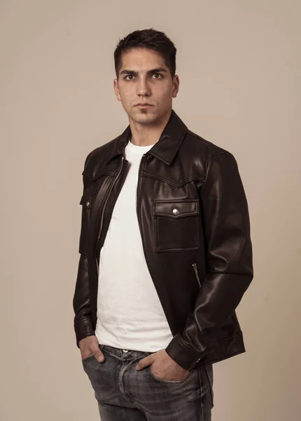Portrait of young attractive fashion hipster man model in his 20s in black leather jacket posing against neutral background looking sexy and masculine. In People, multiracial and Beauty concept.