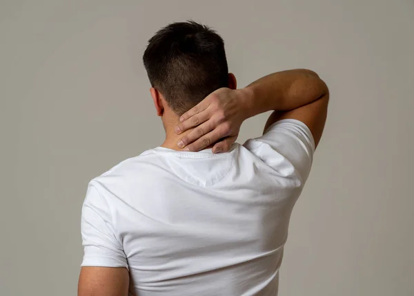 Young muscular fitness man touching and grabbing his neck and upper back suffering cervical pain isolated on neutral background. In sport injury Incorrect posture problems and body health care. — Stock Image Young Muscular Fitness Man Touching Grabbing His Neck Upper Back Royalty Free Stock Images