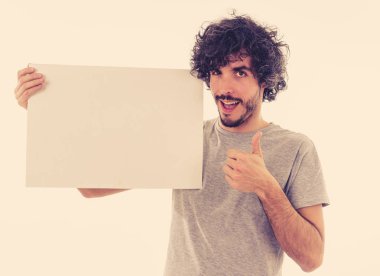Komik ve iyi görünümlü milenyal adam gösteren ve metin için kopya alanı ile boş tahta işaret. Samimi ve heyecanlı genç şık adam reklam için boş poster tutuyor. Pazarlama konsepti.