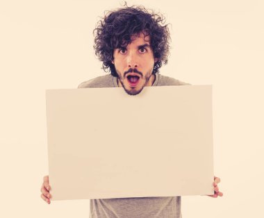 Komik ve iyi görünümlü bin yıllık adam gösteren ve reklam metni için kopya alanı ile boş tahta işaret. Mutlu sürpriz ve büyük reklam şok bakıyor. Pazarlama konsepti.