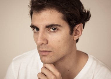 Rahat t-shirt güvenli ve kendinden emin görünümlü kaygısız giden erkek portre yakın. Gülümsüyor ve kameraya bakıyor. Stüdyo çekimi. Doğal güzellik, insan modelleme ve yaşam tarzı kavramı.