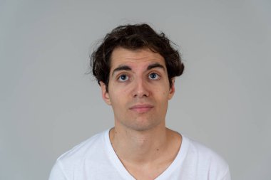 Komik yüzler düşünüyorum. Endişeli genç adamın portresi karıştı. Yeni fikirler, başarı için yaratıcı yollar, yeni diller öğrenme veya eğitim düşünceli erkek düşünme. Nötr arka planda yalıtılmış.