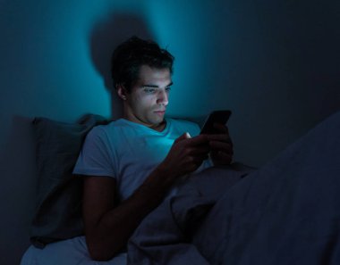 Yaşam tarzı portre cep telefonu bağımlısı adam uyku geç gece yatakta akıllı telefon kontrol sever ve takipçileri, sohbet, flört, sosyal medyada dating kullanarak. Internet bağımlılığı ve mobil istismar.