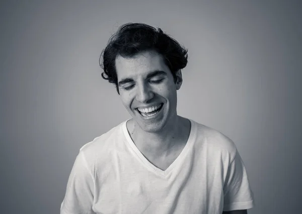 Black and white portrait of carefree male in casual t-shirt looking confident and self-assured. Smiling and staring at camera. Studio shot. In natural beauty, people modeling and lifestyle concept.