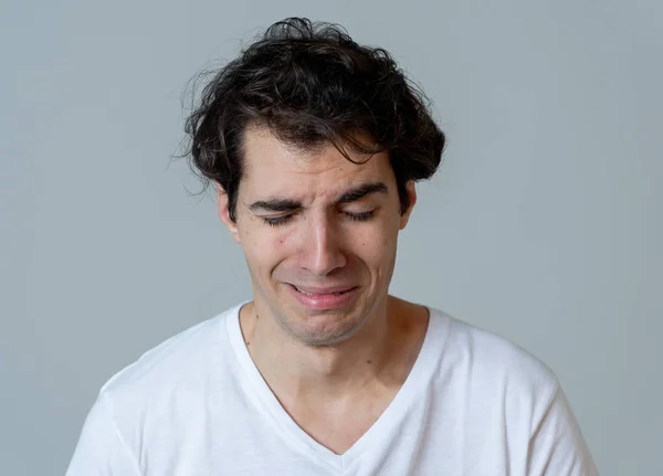 Portrait of young sad man crying in emotional pain looking desperate and distressed. Millennial male suffering from depression. In mental health and sensitive men emotions and feelings reaction.
