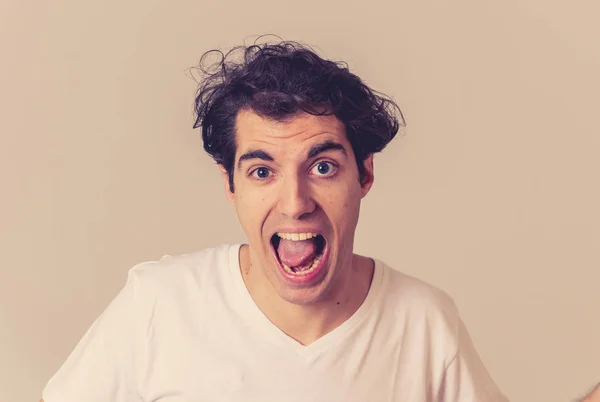 Portrait of young happy man with funny hilarious faces having fun. Millennial male making silly amusing gestures isolated against neutral background. In People human emotions and facial expressions.