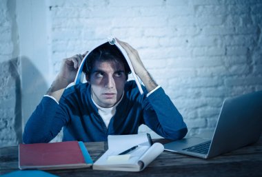 Aşırı çalıştı ve stresli genç öğrenci laptop duygu sıkıntılı yorgun endişeli ve üzücü yoruldu gece geç saatlere kadar sınava hazırlanıyor. Moody koyu ışık. Online öğrenme, üniversite eğitimi ve stres.