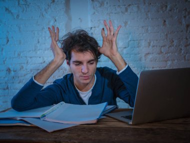 Aşırı çalıştı ve stresli genç öğrenci laptop duygu sıkıntılı yorgun endişeli ve üzücü yoruldu gece geç saatlere kadar sınava hazırlanıyor. Moody koyu ışık. Online öğrenme, üniversite eğitimi ve stres.