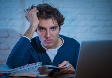 Aşırı çalıştı ve stresli genç öğrenci laptop duygu sıkıntılı yorgun endişeli ve üzücü yoruldu gece geç saatlere kadar sınava hazırlanıyor. Moody koyu ışık. Online öğrenme, üniversite eğitimi ve stres.
