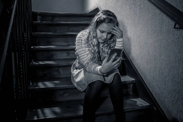 悲しい落ち込んだ少女は 絶望的 虐待を感じ 階段に座って携帯電話でサイバーいじめの被害者 オンラインストーカーによるテキストメッセージでいじめられ嫌がらせを受けた子ども — ストック写真