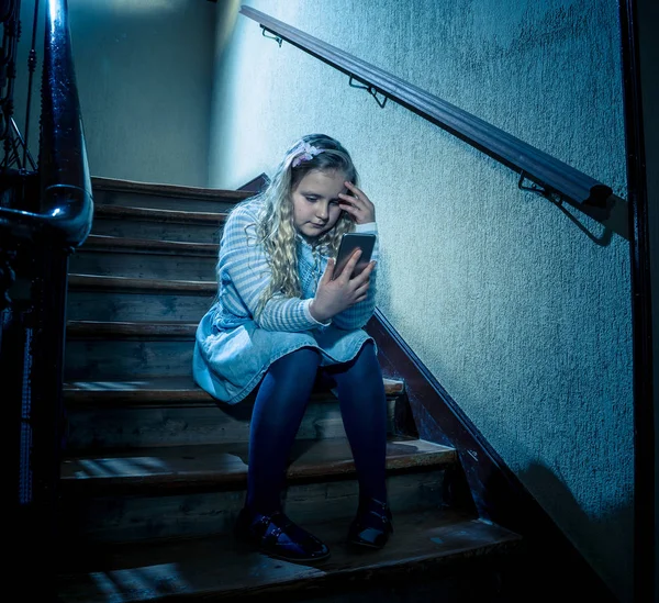 Sad depressed girl Bullied by text message humiliated online social media by classmates. Sad depressed young girl victim of cyberbullying by mobile phone sitting on stairs feeling lonely hopeless.