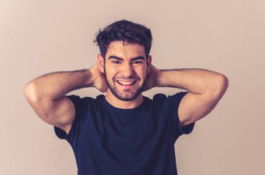 Pozitif insan yüz ifadeleri ve duygular. Mutlu yüz gülümseyen ve kamera neşeli jestleri ile onun 20s yakışıklı genç erkek portre. Yakın çekim nötr arka planda yalıtılmış.
