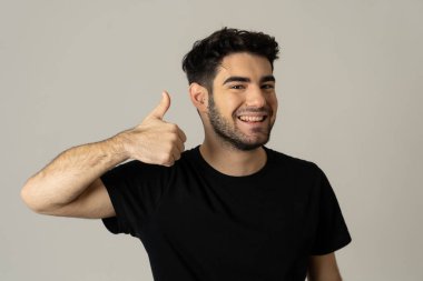 İyi görünümlü genç adamın portresi, neşeli, mutlu ve memnun duygu başparmak kadar gösterir. Genç mutlu öğrenci erkek beyaz arka planda izole neşeli onay jest kadar başparmak yapma.