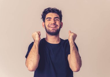 Genç adam onun hedefe ulaşmak, piyango yeme veya yüz ifade insan duyguları ve gri izole ve mutlu yüz ifadesi büyük bir başarı olan kutluyor portresi.