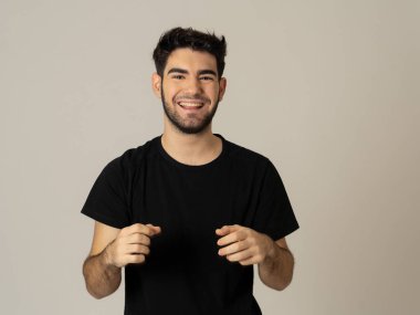 Pozitif insan yüz ifadeleri ve duygular. Mutlu yüz gülümseyen ve kamera neşeli jestleri ile onun 20s yakışıklı genç erkek portre. Yakın çekim nötr arka planda yalıtılmış.