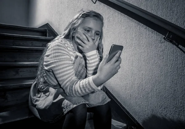 悲しい落ち込んだ少女は クラスメートによってオンラインソーシャルメディアを屈辱したテキストメッセージでいじめられました 悲しい落ち込んだ少女のサイバーいじめの犠牲者は 孤独な絶望感を感じて階段に座って携帯電話で — ストック写真