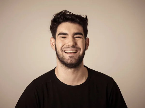 Positive human facial expressions and emotions. Portrait of handsome young male in his 20s with happy face smiling and making cheerful gestures at the camera. Close up Isolated on neutral background.