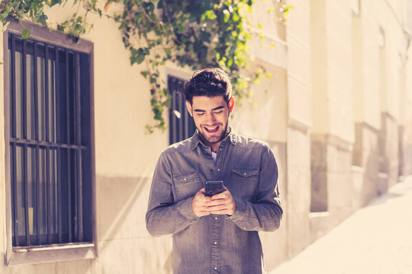 Fashion college man in his twenty ties happy checking blog or chatting on the internet with friends on smart phone app in european outdoors city. В области коммуникационных технологий и путешествий Европа
.