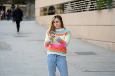 Güzel mutlu öğrenci kadın şehir sokak dışında sosyal medya uygulamaları kullanarak akıllı telefon online sohbet. Şık giysiler giyen güzel genç ücretsiz duygu. İnsanlar, yaşam tarzı ve teknoloji kullanımı.
