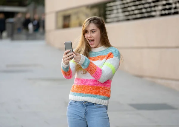 Pretty teenager woman happy and excited on smart mobile phone checking surprised lots of likes and followers on her blog. Urban background. In technology Communications online Trends and Blogging.