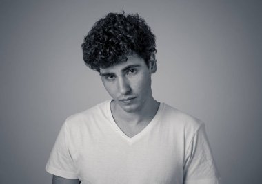 Onun 20s genç çekici şık moda adam rahat giysiler ve nötr arka plan karşı poz koyu kıvırcık saç seksi görünümlü. Tatlı ve erkeksi modelportresi. İnsanlar ve Güzellik kavramı.