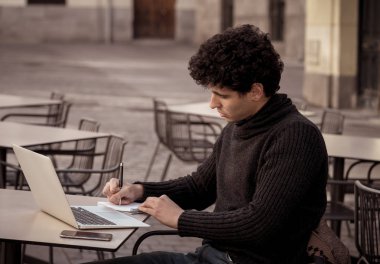 Yakışıklı genç adam bir Avrupa şehir kahve dükkanında teras dışında dizüstü bilgisayar üzerinde çalışıyor. Öğrenci Duygu mutlu ve memnun. Avrupa'da online eğitim ve teknoloji konsepti nde seyahat.