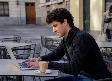 Yakışıklı genç adam bir Avrupa şehir kahve dükkanında teras dışında dizüstü bilgisayar üzerinde çalışıyor. Öğrenci Duygu mutlu ve memnun. Avrupa'da online eğitim ve teknoloji konsepti nde seyahat.