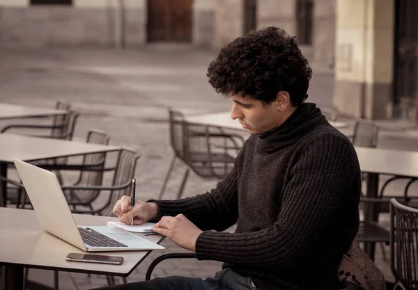 Yakışıklı genç adam bir Avrupa şehir kahve dükkanında teras dışında dizüstü bilgisayar üzerinde çalışıyor. Öğrenci Duygu mutlu ve memnun. Avrupa'da online eğitim ve teknoloji konsepti nde seyahat.