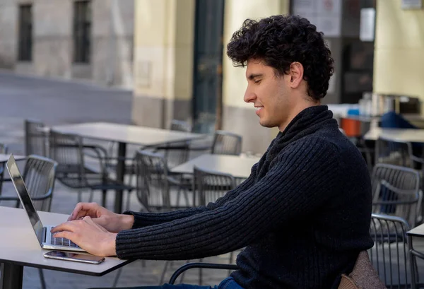 Yakışıklı genç adam bir Avrupa şehir kahve dükkanında teras dışında dizüstü bilgisayar üzerinde çalışıyor. Öğrenci Duygu mutlu ve memnun. Avrupa'da online eğitim ve teknoloji konsepti nde seyahat.