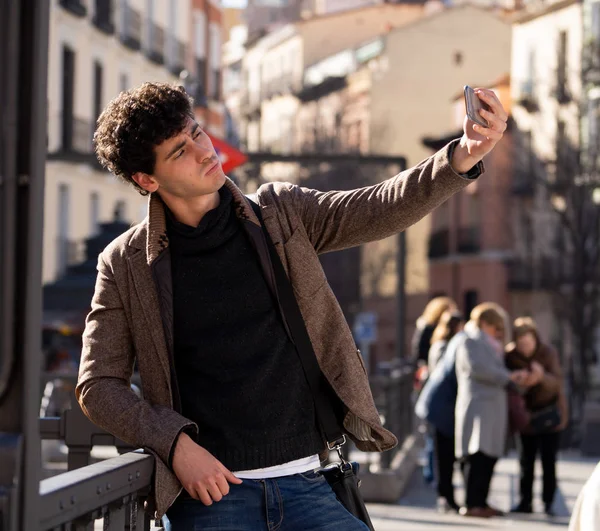Heyecanlı Trendy genç adam selfie veya Avrupa şehir Caddesi veya üniversite kampüsünde tatil akıllı cep telefonu bloglama alarak. Tatil ve teknoloji bağlantı ve sosyal medya konsepti.