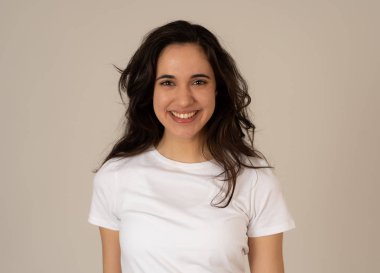 Mutlu yüz güzel gülümseme ve uzun siyah saçlı çekici esmer genç latin kadının yakın portresi. Nötr arka planda izole edilmiş. İnsanlar, pozitif insan yüz ifadesi ve duygu.