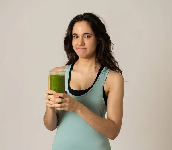 ダイエットデトックススムージードリンクの退屈なジェスチャーを示す健康的な緑のジュースを保持している魅力的なダイエット女の子 健康食品 栄養フィットネスと減量の概念で灰色の背景に隔離 — ストック写真