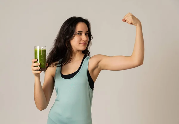 Fitness woman happy smiling holding glass of green vegetable smoothie posing happy and cute after training exercise felling fit and strong. In Body care Fitness Diet Nutrition and Healthy Lifestyle.