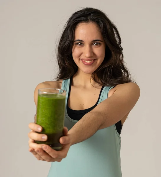 Fitness woman happy smiling holding glass of green vegetable smoothie after running or workout. Portrait isolated with copy space. Beauty Health Fitness Diet Nutrition and healthy Lifestyle concept.