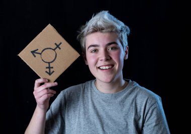 İyi görünümlü mutlu ve gururlu trans genç bir karton plaka üzerine çizilmiş transseksüel sembolü tutan. Cinsiyet kimliği ve çeşitliliğinin kavramsal imgesi. İnsan hakları ve eşitlik kampanyası.