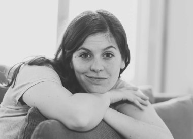 Kadın dinlenme zamanı. Yaşam tarzı siyah ve beyaz doğal ışık ile evde kanepede oturan güzel bir gülümseme ile çekici genç kadın portresi kadar yakın. In People Well olmak ve eğlence kavramı.