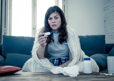 Sağlık ve tıp. Evde kanepede yatan hasta kadın baş ağrısı burun ağrısı ile hasta burun termometre hissi ile yüksek sıcaklık kontrol yorgunluk ve huzursuz işe gitmek mümkün değil.