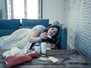 Sağlık ve tıp. Evde kanepede yatan hasta kadın baş ağrısı burun ağrısı ile hasta burun termometre hissi ile yüksek sıcaklık kontrol yorgunluk ve huzursuz işe gitmek mümkün değil.