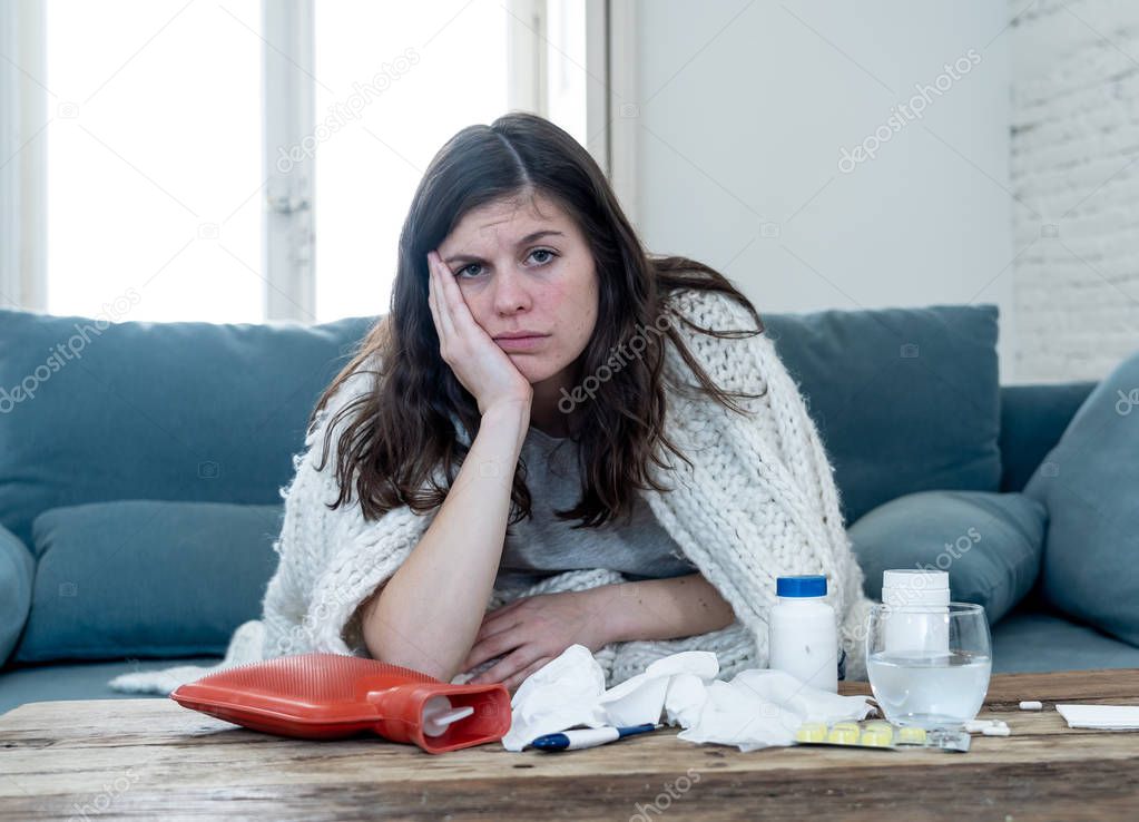 Sick attractive woman under blanket feeling unwell with headache sore nose high temperature feeling fatigue and restless at home not being able to go to work in health care concept.